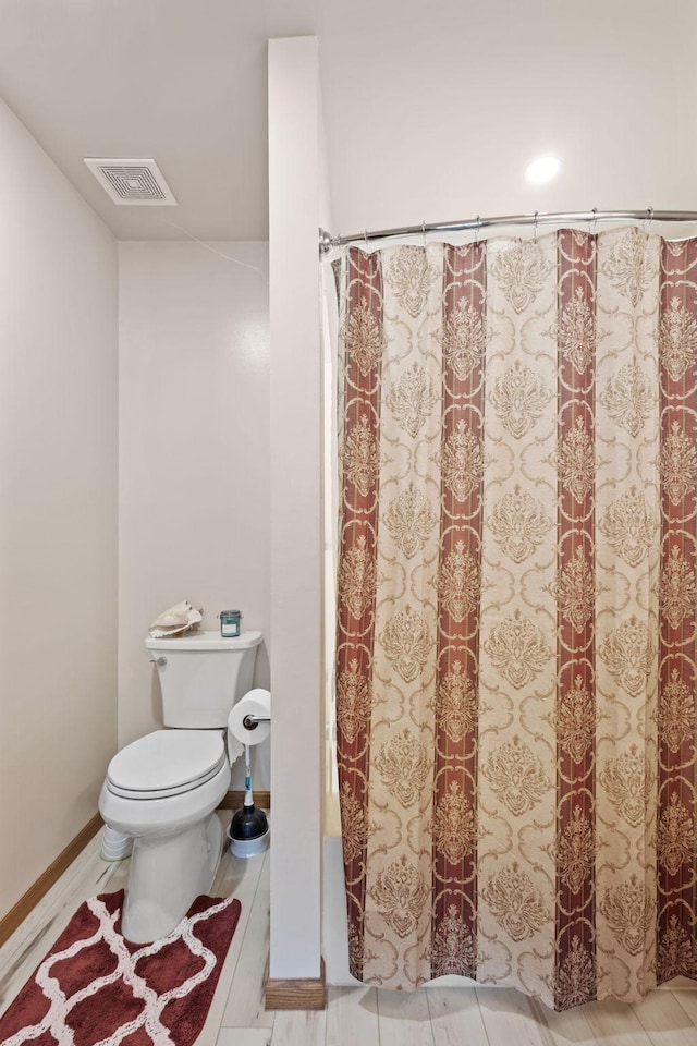 full bath featuring a shower with shower curtain, toilet, baseboards, and visible vents