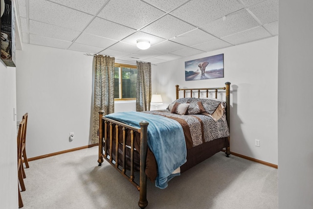 carpeted bedroom featuring a paneled ceiling and baseboards