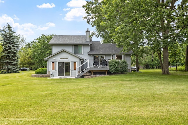 back of house featuring a shingled roof, a wooden deck, stairs, a chimney, and a yard