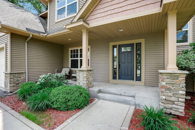 view of exterior entry featuring stone siding, covered porch, and roof with shingles