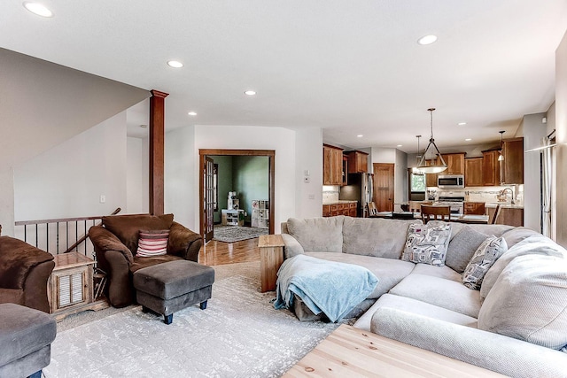 living area with ornate columns, recessed lighting, and light wood-style floors