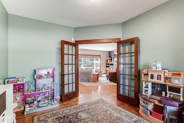 home office featuring wood finished floors, french doors, and a textured ceiling