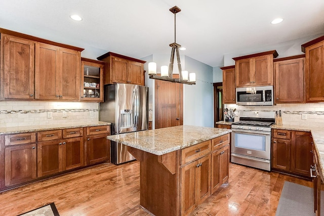 kitchen featuring appliances with stainless steel finishes, light wood-style flooring, brown cabinetry, and a center island