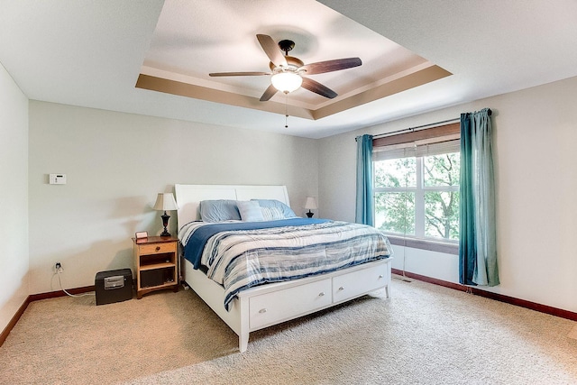 bedroom featuring a tray ceiling, baseboards, a ceiling fan, and carpet flooring