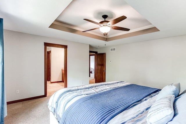 bedroom with visible vents, ceiling fan, baseboards, light carpet, and a raised ceiling