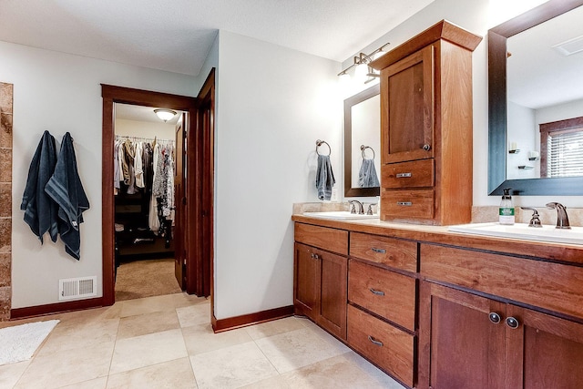 full bathroom with double vanity, a spacious closet, and a sink