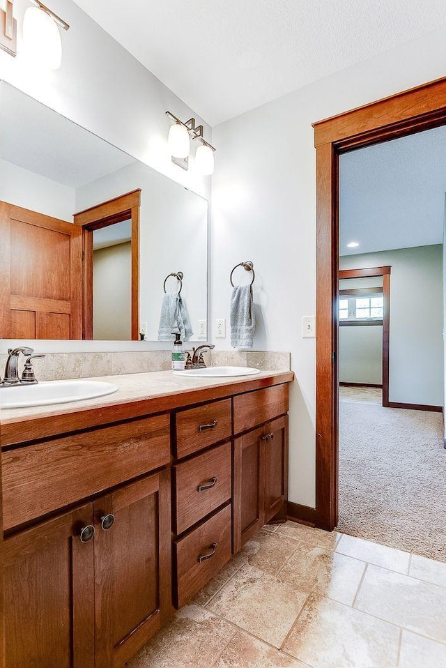 full bath featuring double vanity, baseboards, and a sink