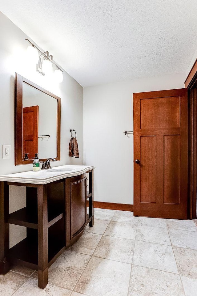 bathroom with vanity, baseboards, and a textured ceiling