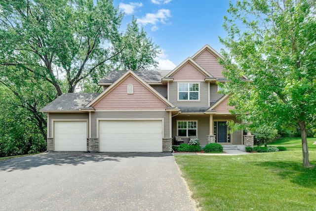 craftsman inspired home with a garage, stone siding, a front yard, and aphalt driveway