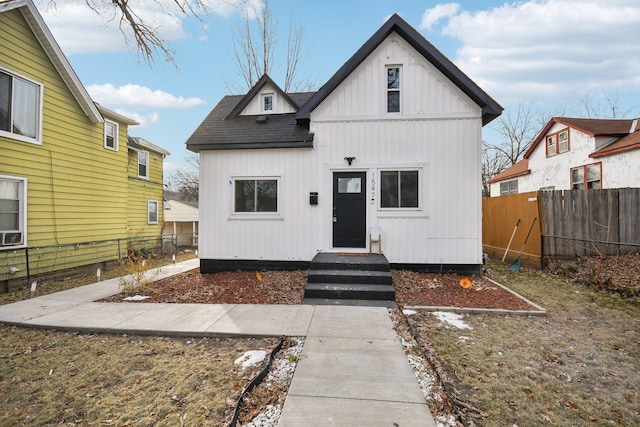 view of front of property with roof with shingles and fence