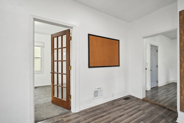 spare room featuring dark wood-style floors, visible vents, and baseboards