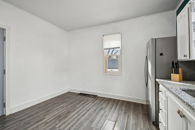 kitchen with light stone counters, baseboards, dark wood-style flooring, freestanding refrigerator, and white cabinetry