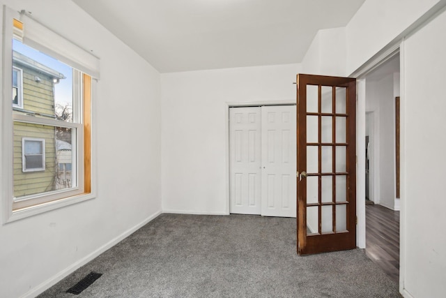 unfurnished bedroom with a closet, visible vents, carpet flooring, and baseboards