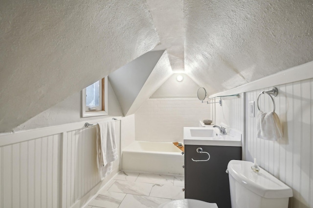 full bath featuring toilet, a tub to relax in, vaulted ceiling, marble finish floor, and a textured ceiling