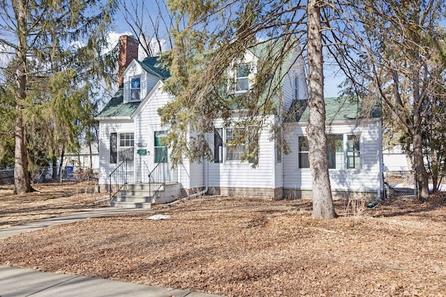 cape cod house with a chimney and fence