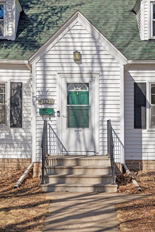 entrance to property featuring a shingled roof