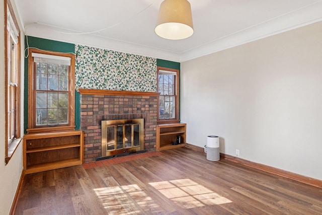 unfurnished living room featuring baseboards, wood finished floors, a fireplace, and crown molding