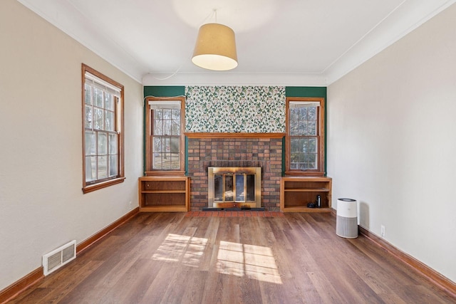 unfurnished living room featuring visible vents, wood finished floors, a fireplace, crown molding, and baseboards