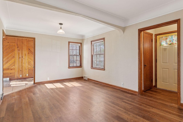 spare room with visible vents, baseboards, ornamental molding, wood finished floors, and arched walkways