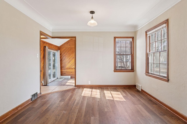 unfurnished room featuring visible vents, ornamental molding, baseboards, and wood finished floors