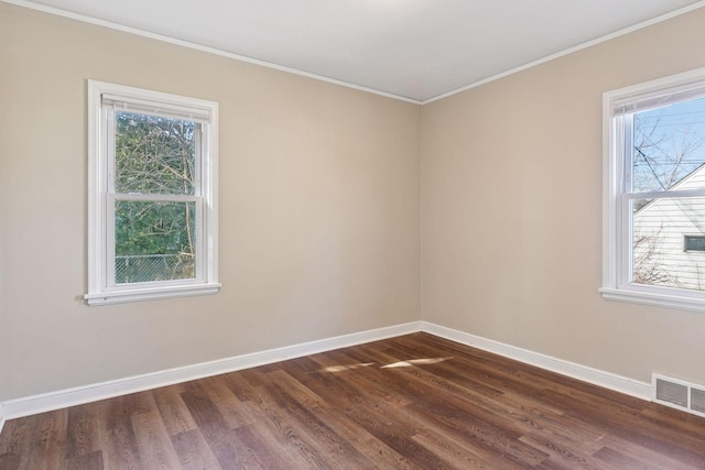 unfurnished room featuring dark wood-type flooring, baseboards, visible vents, and ornamental molding