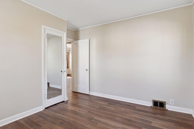 spare room featuring ornamental molding, dark wood-style floors, visible vents, and baseboards