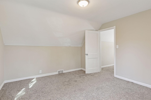 spare room featuring visible vents, baseboards, carpet flooring, and vaulted ceiling