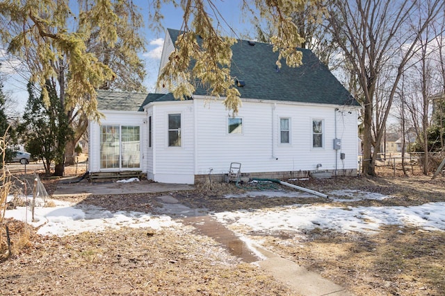 rear view of property featuring a shingled roof and fence