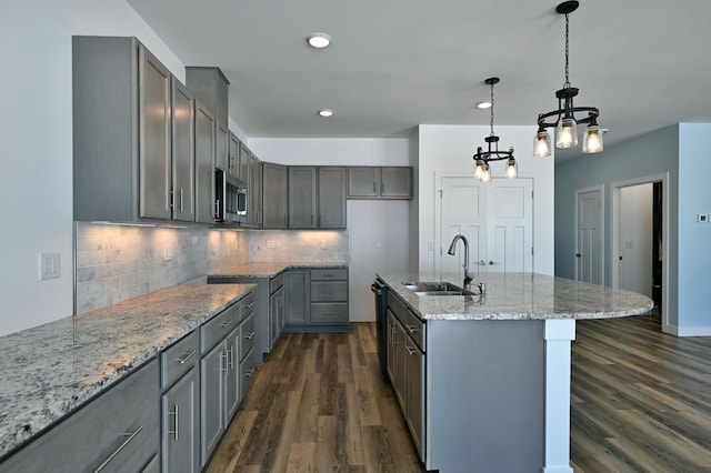 kitchen with a sink, stainless steel microwave, gray cabinetry, and dark wood-style floors