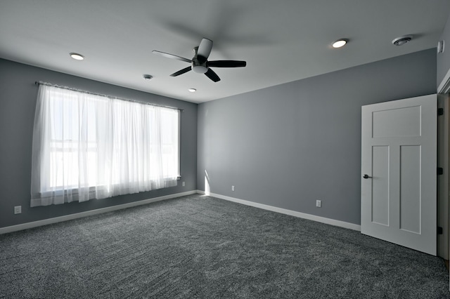 unfurnished room with a ceiling fan, baseboards, and dark colored carpet