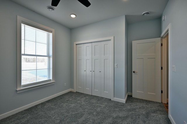 unfurnished bedroom with visible vents, baseboards, dark carpet, a closet, and a ceiling fan