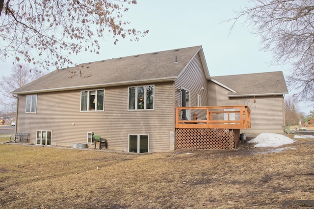 rear view of property featuring a shingled roof, a lawn, and a wooden deck