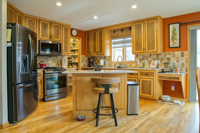 kitchen with light countertops, light wood-style flooring, brown cabinets, and appliances with stainless steel finishes