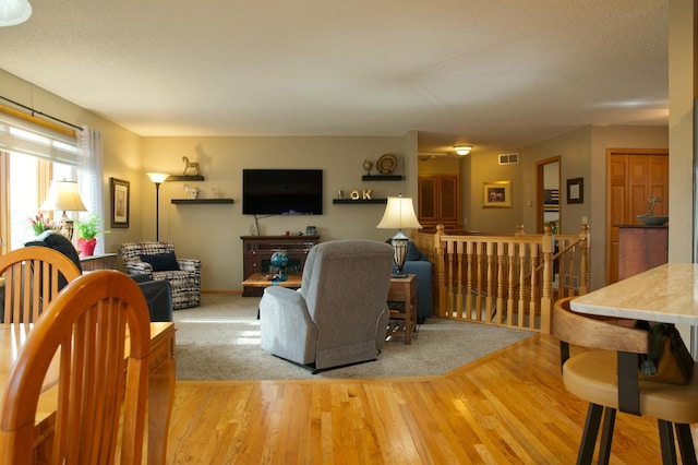 living area with visible vents and wood finished floors