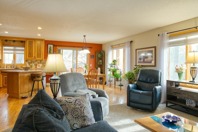 living area featuring recessed lighting, plenty of natural light, light wood-style flooring, and a textured ceiling