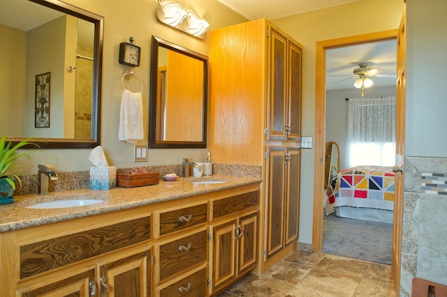 ensuite bathroom featuring double vanity, connected bathroom, a ceiling fan, and a sink