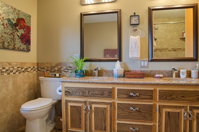 bathroom featuring wainscoting, vanity, toilet, and tile walls