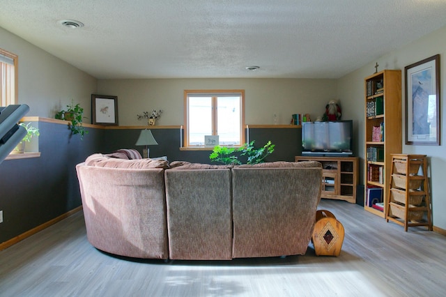 living area with visible vents, a textured ceiling, baseboards, and wood finished floors