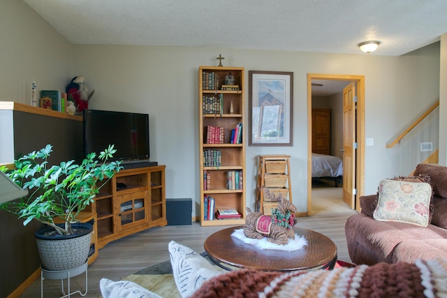 living room with baseboards, a textured ceiling, and wood finished floors