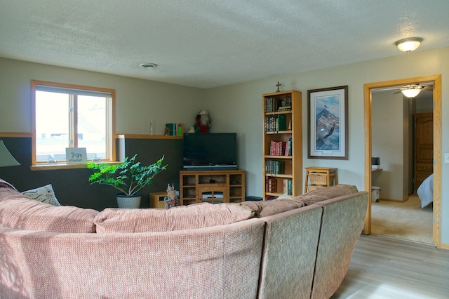 living area with visible vents, a textured ceiling, and wood finished floors