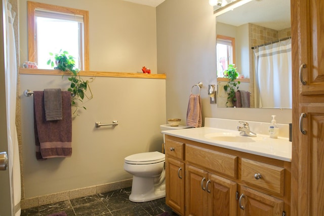 bathroom with a healthy amount of sunlight, toilet, vanity, and baseboards