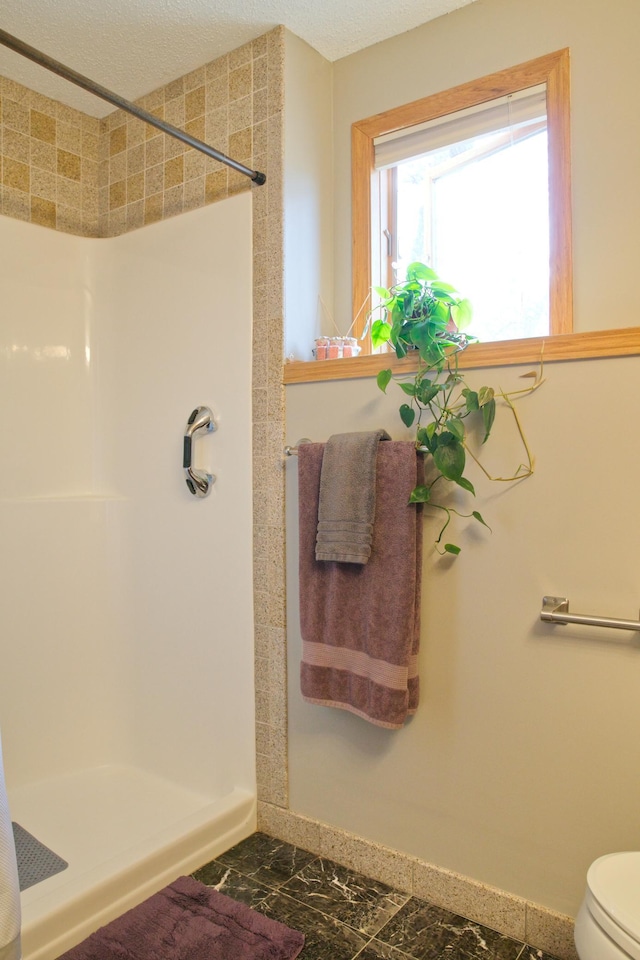 full bathroom featuring toilet, a shower stall, and a textured ceiling