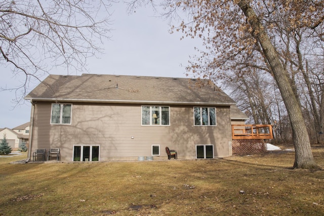 rear view of property featuring a wooden deck, a lawn, and a shingled roof