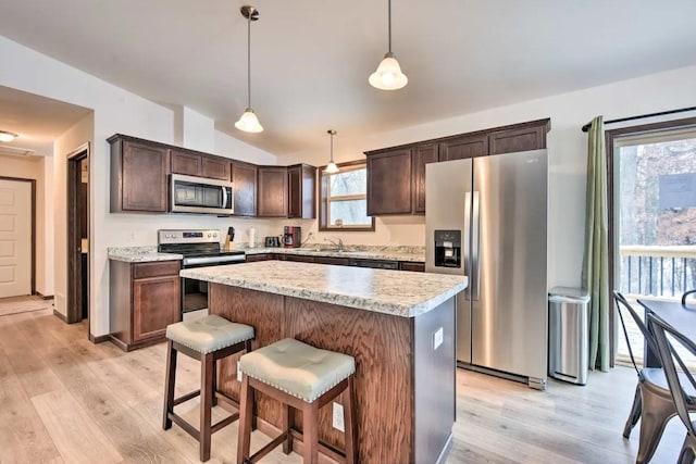 kitchen with dark brown cabinetry, appliances with stainless steel finishes, lofted ceiling, and light wood-style floors