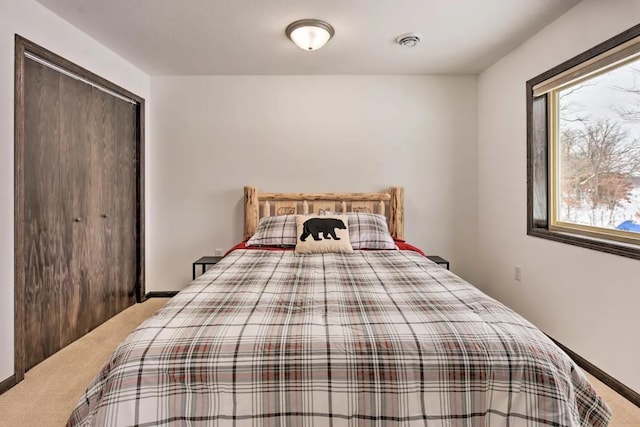 carpeted bedroom with a closet, visible vents, and baseboards