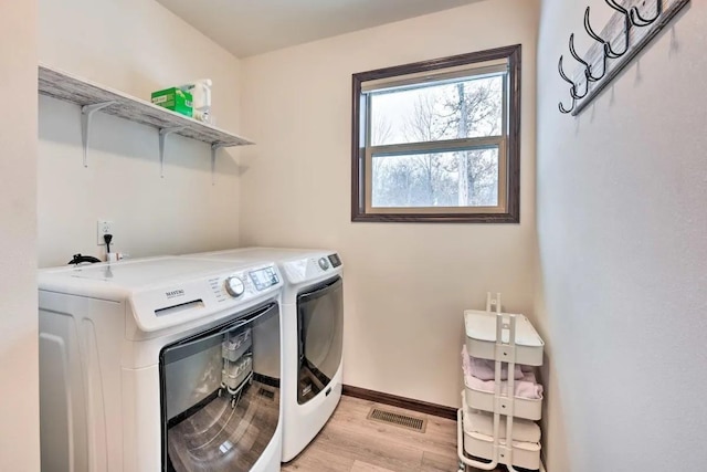 laundry area with visible vents, light wood finished floors, baseboards, laundry area, and separate washer and dryer