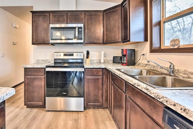 kitchen featuring dark brown cabinets, light wood-style floors, appliances with stainless steel finishes, and a sink