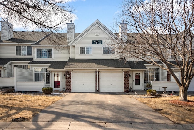 view of front of house with brick siding, driveway, and roof with shingles