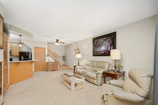 living room with light carpet, stairway, and ceiling fan