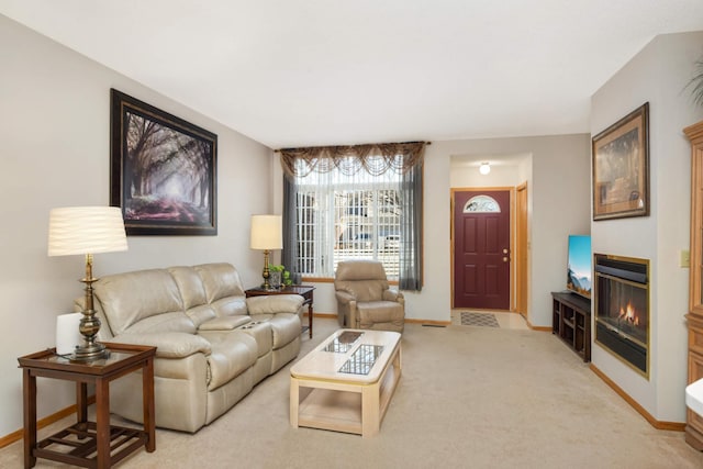 living room with a glass covered fireplace, baseboards, and light carpet